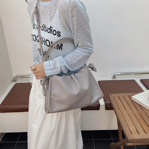 Minimalist grey pleated cloud bag with signature knot detail shown on model shoulder