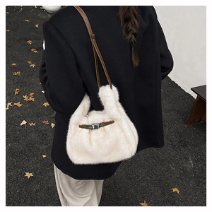 Détail d'un sac à main en peluche blanche avec bandoulière en cuir sur un manteau noir