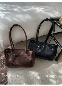 Close-up of retro leather tote bags in brown and black with buckle strap detail
