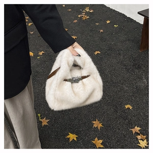 Gros plan du sac à main en peluche blanche avec anses en cuir marron et boucle argentée