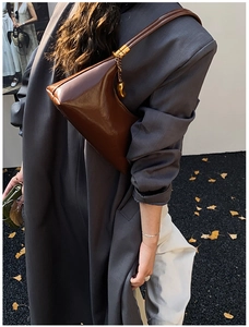 Gros plan du sac bandoulière asymétrique en cuir marron caramel avec finitions dorées