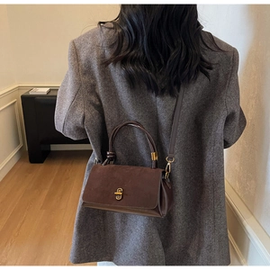 Detailed view of brown patchwork handbag with retro metal buckle on a tweed blazer