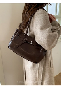 Close-up of dark brown vintage leather shoulder bag with a metal buckle decoration