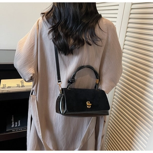 Detail of black crossbody bag featuring matte finish, gold twist lock and woven handle
