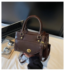 Close-up of a vintage dark brown PU leather handbag with gold twist lock and accessories