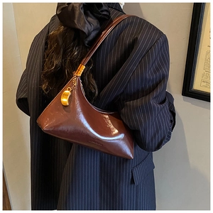 Détail du sac en cuir bordeaux brillant avec chaîne dorée et logo gaufré sur le côté