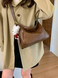 Retro deep brown leather hobo bag with white stitching and cute plush dog pendant charm