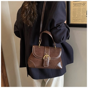 Dettaglio della borsa a sella vintage con cuciture bianche e fibbia dorata su modella