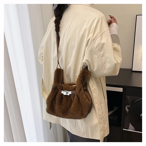 Détail d'un sac à bandoulière en peluche marron avec fermoir métallique et lanière