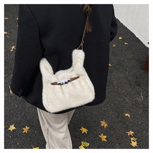 Détail du sac à main en peluche crème avec bandoulière en cuir brun et boucle argentée