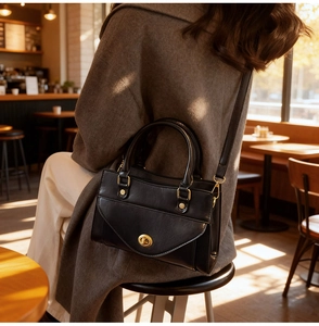 Detail of black leather handbag with a gold metal twist lock for chic urban commuting
