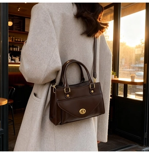 Classic vintage brown handbag detail with golden turn-lock and adjustable leather strap