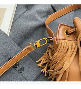 Détail du sac seau vintage avec fermoir en métal doré et franges élégantes en daim