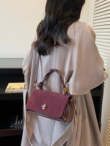Elegant wine red shoulder bag with textured suede flap and unique knotted top handle
