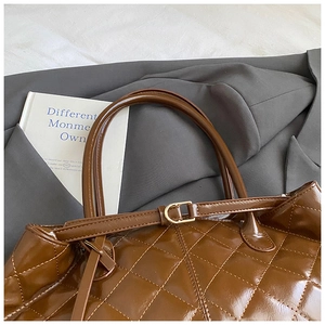 Detail of brown quilted tote bag with glossy finish and gold D-ring hardware