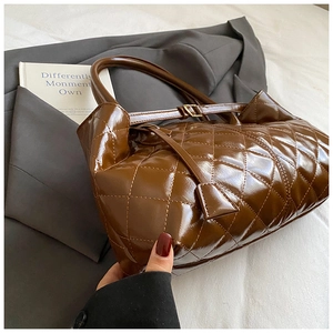 Close-up of brown quilted patent leather tote bag with glossy finish and dual handles