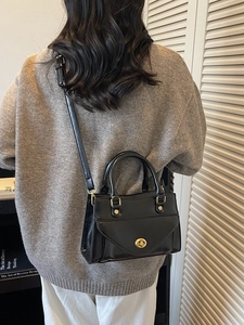 Classic black PU leather tote bag with gold swivel lock shown on model with shoulder strap
