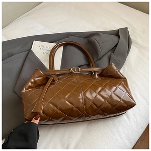 Detail of a brown quilted tote bag with glossy finish and metal buckle strap design
