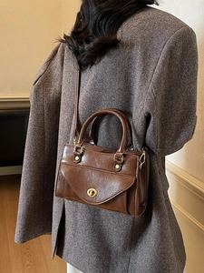 Brown vintage style leather handbag with top handle and gold twist lock shown on model