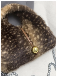 Close-up of faux fur texture with deer print and large gold metallic bead toggle