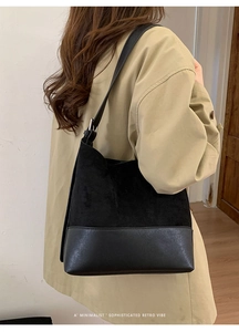 Close-up of a minimalist black suede tote bag with adjustable strap and retro vibe