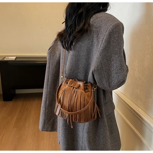 Sac seau vintage marron à franges porté sur un blazer gris à chevrons pour un style chic