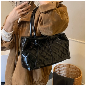 Close-up of black quilted patent leather tote bag showing glossy texture and large capacity