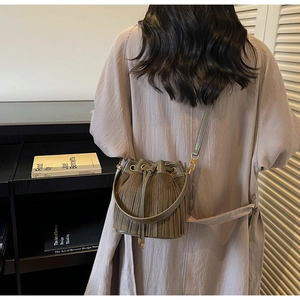 Sac seau vert olive avec franges et cordon de serrage porté sur l'épaule d'une femme