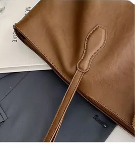Detailed close-up of reinforced stitching on caramel brown leather tote bag straps