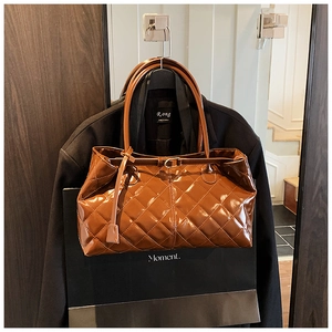 Detailed close-up of dark brown quilted patent leather tote bag with glossy finish