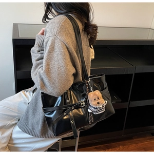 Detail view of black oil wax leather tote bag with stylish eyelet strap and puppy charm