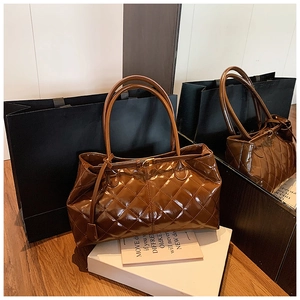 Detail of a brown quilted tote bag in glossy leather with classic diamond stitching pattern