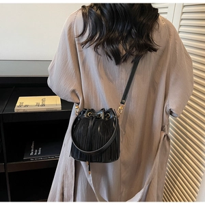 Détail du sac seau noir à franges avec anneau doré et texture en cuir suédé mélangé
