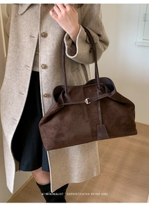 Detail of dark brown faux suede tote bag with slim shoulder straps and metal buckle