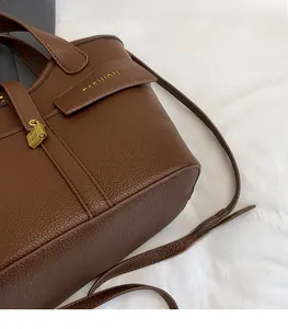 Detail of brown litchi leather bucket bag featuring gold fashion logo and metal padlock