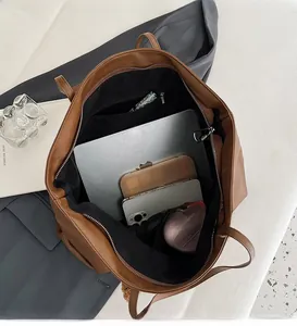 Top view of large brown leather tote bag interior with multiple compartments and a laptop