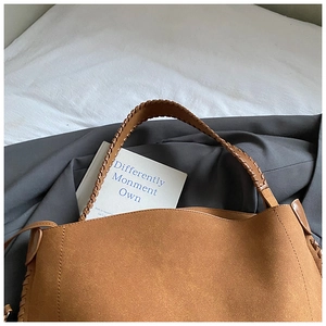Détail du sac cabas en daim marron avec bandoulières tressées et finitions bohèmes