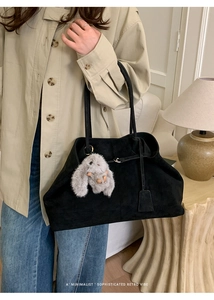 Minimalist black suede tote bag detail featuring a cute grey plush bunny charm accessory