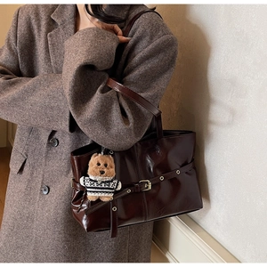 Detail of dark brown wax leather tote bag with teddy bear charm and metal buckle strap