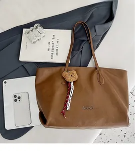 Top view of large brown tote bag with leather texture and cute plush bear charm detail