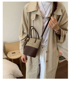 Detail view of two-tone bucket bag in beige suede and brown leather on model