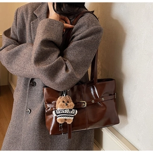 Detail of dark brown leather tote bag featuring pleated texture and cute puppy charm