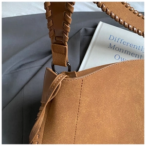 Détail de la bandoulière en cuir tressé et boucle en métal d'un sac cabas marron