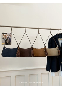 Detail view of four minimalist suede baguette bags in navy, coffee, tan and beige colors