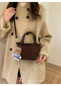 Detail view of retro brown frosted suede bucket bag with a cute teddy bear charm