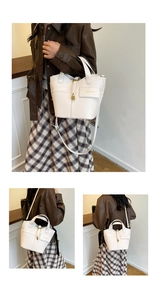 Detail of white litchi pattern bucket bag with golden padlock and fashion plaque