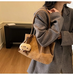 Brown suede tote bag with plush charm shown on a grey wool coat for autumn-winter style