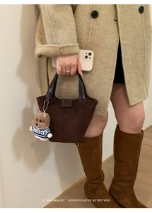 Detail der dunkelbraunen Wildleder-Beuteltasche mit Ledergriff und Teddybär-Anhänger