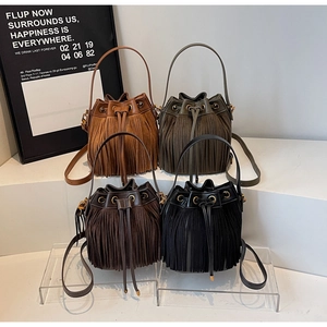 Détail de sacs seaux mats vintage avec de longues franges en quatre couleurs en étalage