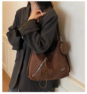 Close-up of brown suede hobo bag with matching round coin purse and silver zippers
